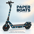 Paper Boats auf Segway Ninebot E3: cremefarbene und korallfarbene Papierboote auf Nachtblau, originale graue Trittmatte erhalten; Felgen separat.