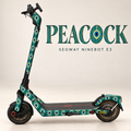 Segway Ninebot E3 mit PEACOCK Skin: Pfauenfeder-Ornamente in Petrol, Smaragd, Türkis, Blau und Ocker. Designvisualisierung mit originaler grauer Trittmatte.