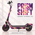 Prism Shift auf Ninebot E3 – Violett, Rosé und Amber mit dunklen Facetten. Originale Trittmatte bleibt; Felgenaufkleber separat, nicht im Skin enthalten.